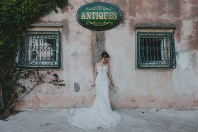 女人穿着婚纱站在墙附近拿着鲜花

